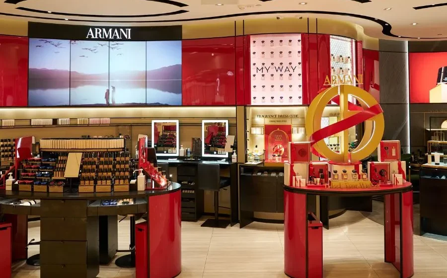 Giorgio Armani em reunião de negócios com logos da LVMH, L'Oréal e EssilorLuxottica representando negociação de €10 bi