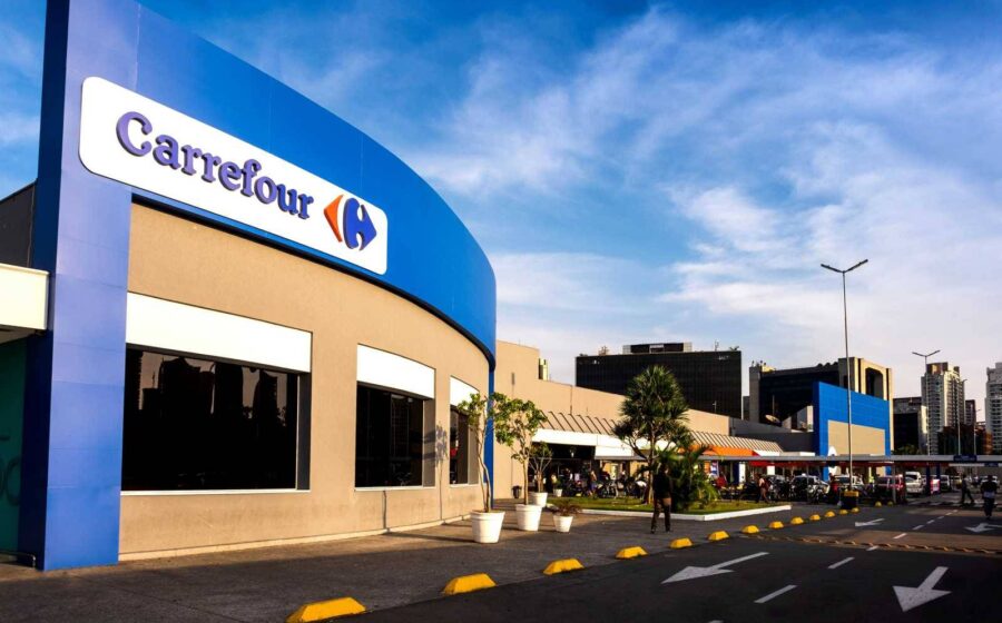 Logo do Comper e Carrefour com setas indicando aquisição de 21 lojas por R$ 360 milhões
