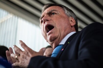 Jair Bolsonaro discursa para apoiadores com gesto de punho cerrado, simbolizando narrativa de perseguição política
