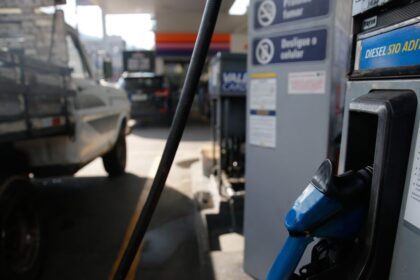Bomba de combustível em posto de gasolina com preços elevados, simbolizando medidas do governo contra alta do diesel e multas bilionárias