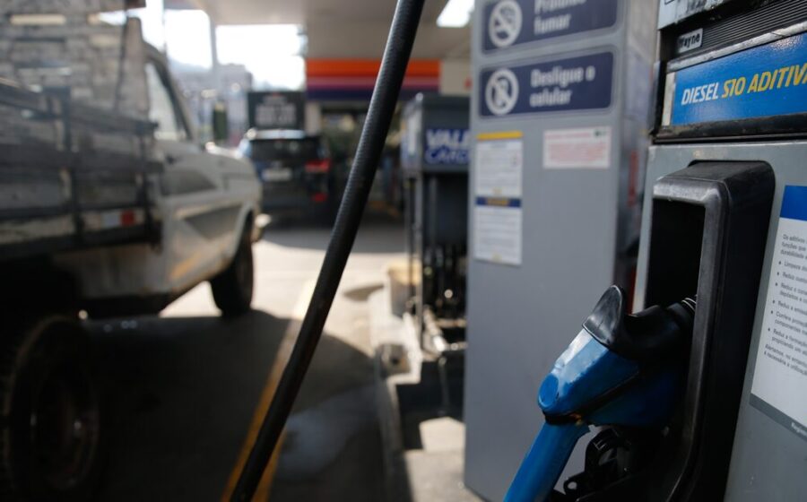 Bomba de combustível em posto de gasolina com preços elevados, simbolizando medidas do governo contra alta do diesel e multas bilionárias