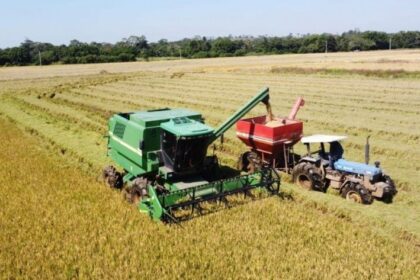 Trator agrícola parado em lavoura alagada no RS com tanque de diesel vazio ao lado