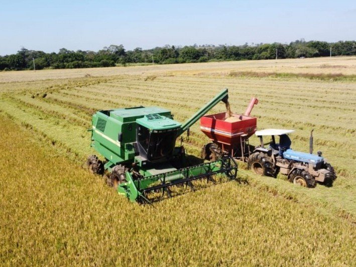 Trator agrícola parado em lavoura alagada no RS com tanque de diesel vazio ao lado