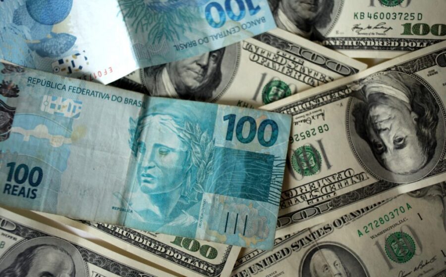 Gráfico mostra projeção do dólar entre R$ 4,90 e R$ 5,50 com urna eletrônica brasileira ao fundo