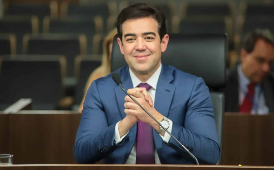 Bruno Dantas em cerimônia de posse como CEO da Avibras, com logotipo da empresa e bandeira do Brasil ao fundo