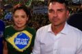 Flávio Bolsonaro discursa ao microfone com fundo desfocado, gesto de mão firme