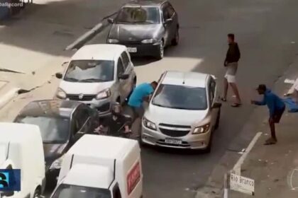 Motorista de aplicativo com celular escondido no painel do carro em rua movimentada de São Paulo