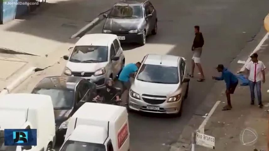 Motorista de aplicativo com celular escondido no painel do carro em rua movimentada de São Paulo