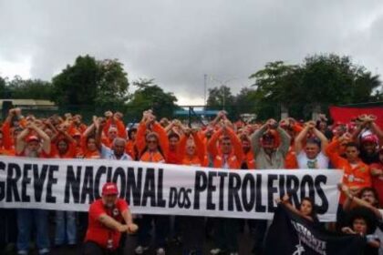 Funcionários da Caixa em greve diante de agência com faixa de paralisação