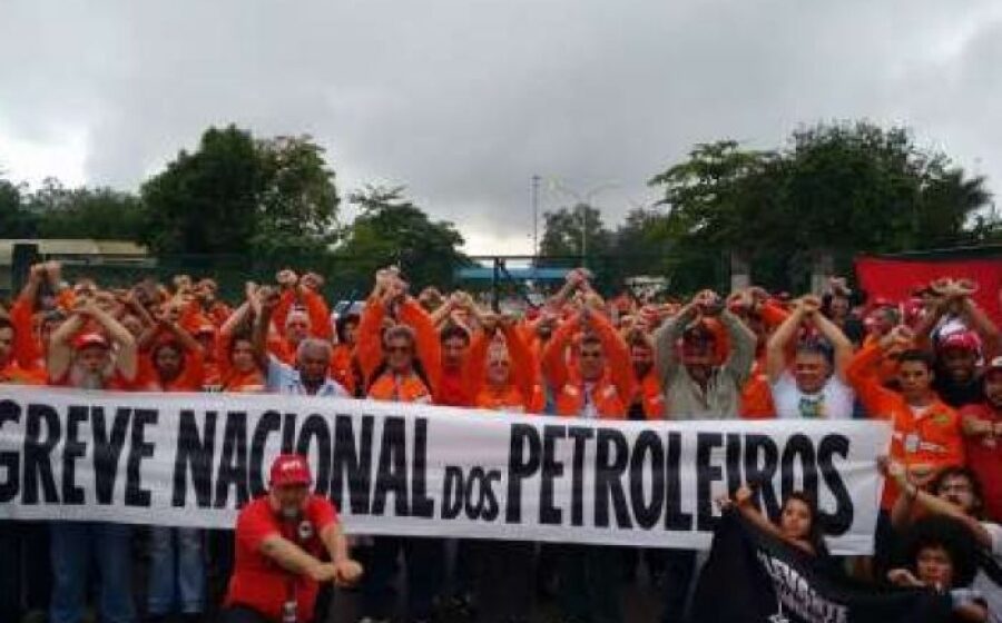 Funcionários da Caixa em greve diante de agência com faixa de paralisação