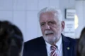 Senador Jaques Wagner em sessão no Congresso, com sobreposição de notas de R$ 100 e documentos de investigação