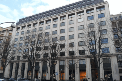 Sede da LVMH em Paris com logotipo Louis Vuitton e gráfico de queda acionária