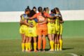 Jogadoras de futebol feminino comemorando gol em estádio brasileiro, representando nova lei de investimento obrigatório