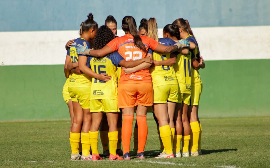 Jogadoras de futebol feminino comemorando gol em estádio brasileiro, representando nova lei de investimento obrigatório
