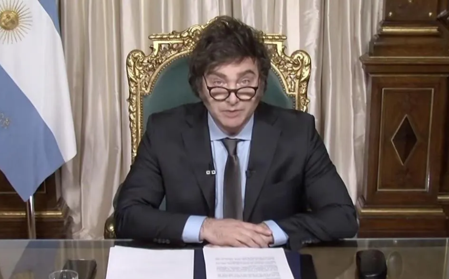 Javier Milei discursa com gráficos de superávit fiscal e inflação em queda, enquanto população argentina enfrenta pobreza nas ruas