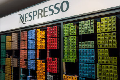 Cápsulas Nespresso coloridas e máquina moderna sobre mesa, simbolizando reposicionamento da marca aos 40 anos