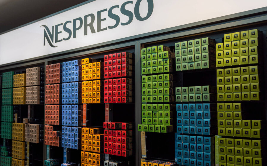 Cápsulas Nespresso coloridas e máquina moderna sobre mesa, simbolizando reposicionamento da marca aos 40 anos