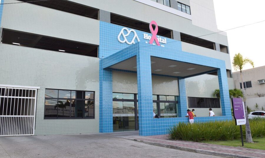 Fachada de hospital privado com selo de qualidade e balança da justiça simbolizando nova lei de fiscalização