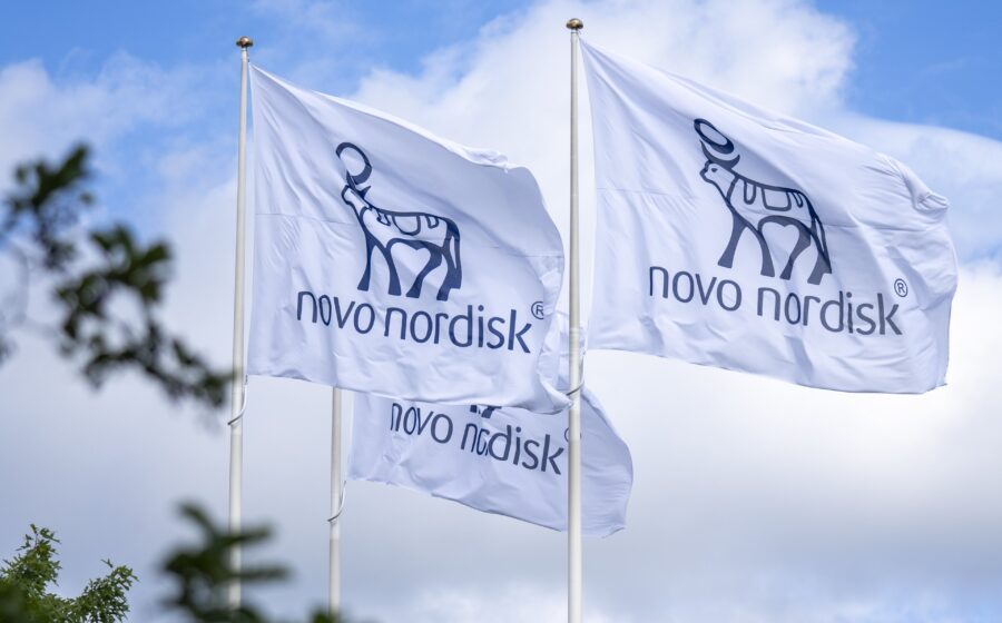 Logos da Novo Nordisk e Jiangsu Hengrui sobre fundo de comprimidos e gráfico de ações