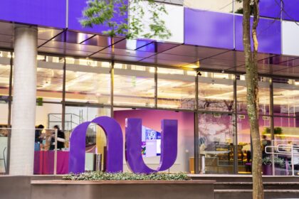 Gráfico de ações do Nubank em queda livre com ícone de fusão corporativa e bandeira do Reino Unido