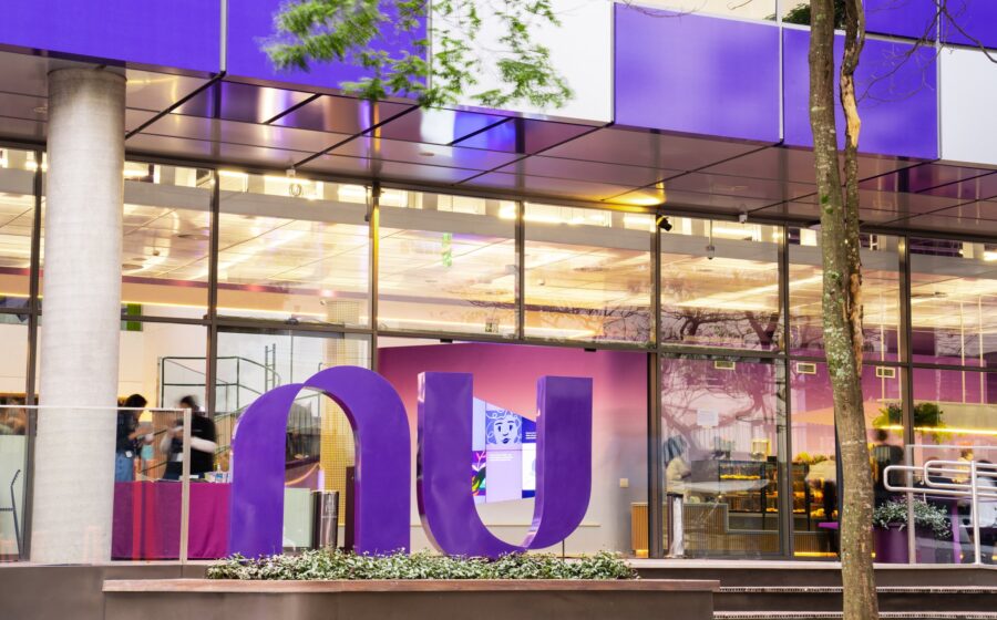 Gráfico de ações do Nubank em queda livre com ícone de fusão corporativa e bandeira do Reino Unido