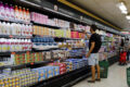 Carrinho de supermercado com produtos básicos e etiquetas de preço alto, simbolizando inflação alimentar pré-eleição