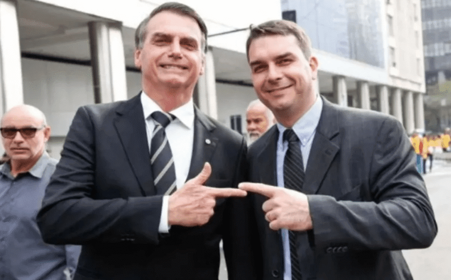 Aperto de mão entre bandeiras dos EUA e Brasil sob sombra de figuras políticas