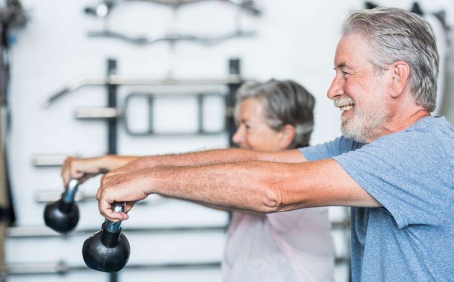 Carlos Roberto Castagini, 66 anos, e Lenita Capeli, 65 anos, treinando musculação pesada no interior de São Paulo, exemplificando longevidade produtiva e prevenção da sarcopenia