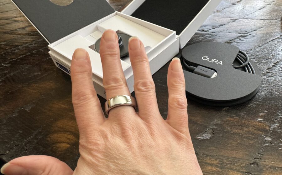 Anel inteligente Oura Ring dourado sobre superfície reflexiva, símbolo de tecnologia vestível