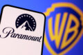 Logotipo Paramount e Warner Bros. Discovery com gráficos financeiros de fusão bilionária
