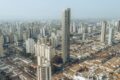 Canteiro de obras em São Paulo com estrutura metálica pré-fabricada e módulos de banheiro sendo instalados por poucos operários