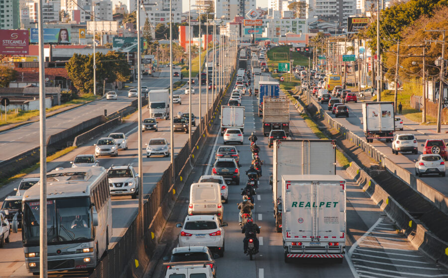 Rodovia brasileira em obras com placa de concessão pública-privada simbolizando investimentos atrasados