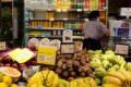 Supermercado aberto em feriado com clientes fazendo compras, faixa indicando funcionamento normal