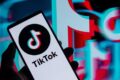 Logotipo do TikTok com relógio marcando 2 horas e símbolo de dólar, representando limite de uso e multa bilionária no Alabama