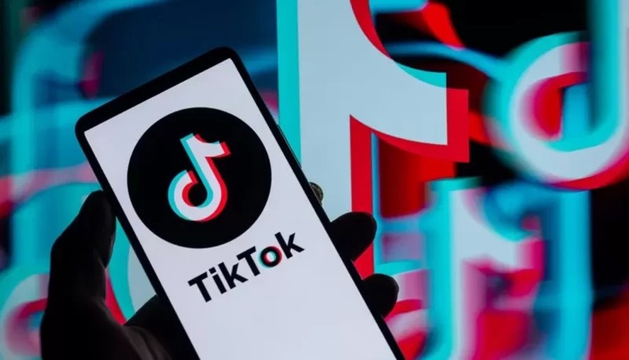 Logotipo do TikTok com relógio marcando 2 horas e símbolo de dólar, representando limite de uso e multa bilionária no Alabama