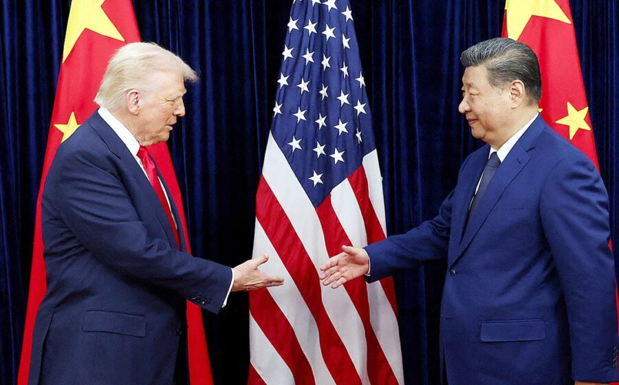 Trump e Xi Jinping apertam as mãos em cúpula diplomática com bandeiras dos EUA e China ao fundo