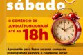 Vitrine de loja em Divinópolis com placa de horário estendido até 18h no sábado véspera do Dia das Crianças