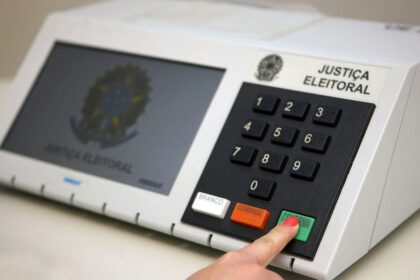 Urna eletrônica sendo substituída por mesário em local de votação na Paraíba durante segundo turno 2026