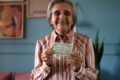 Idosa votando em urna eletrônica com campanha Vovó Vota ao fundo