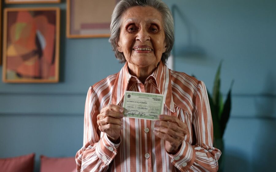 Idosa votando em urna eletrônica com campanha Vovó Vota ao fundo