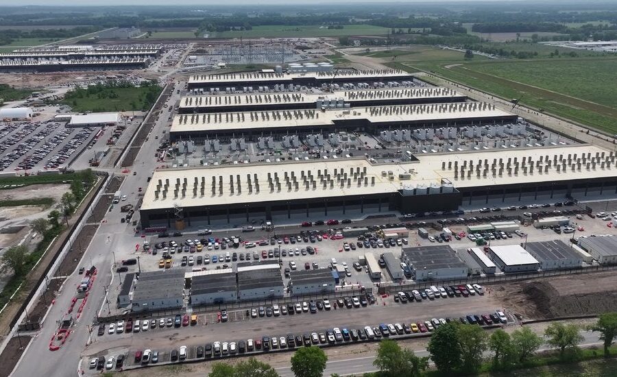 Data center da Amazon com comunidade local ao fundo, simbolizando investimento de US$ 1 bi em mitigação de impactos