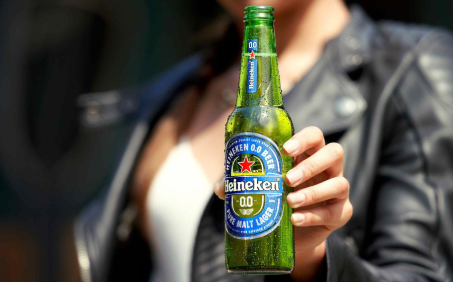 Garrafa verde Heineken 0.0 com rótulo azul e logotipo da estrela vermelha sobre mesa