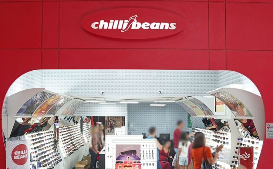 Logotipo da Chilli Beans sobre fundo de loja com óculos escuros expostos, símbolo da recuperação extrajudicial de R$ 340 milhões