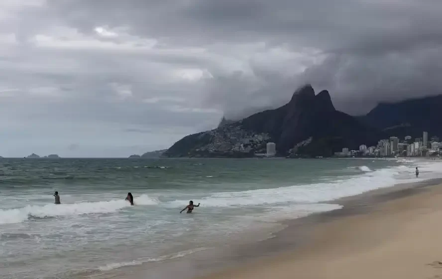 Eleitor com guarda-chuva vota sob chuva forte e céu nublado no Rio de Janeiro