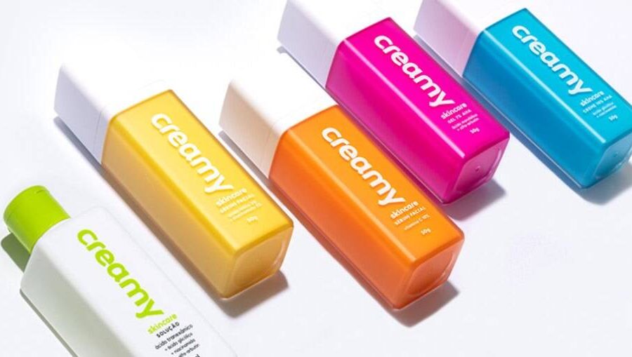 Quatro produtos Creamy skincare minimalistas: limpador, hidratante, protetor solar e complementar sobre fundo neutro
