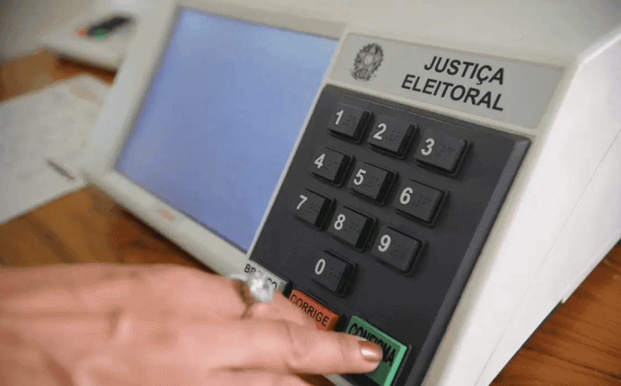 Urna eletrônica e título de eleitor em mesa de votação nas eleições suplementares em municípios de São Paulo