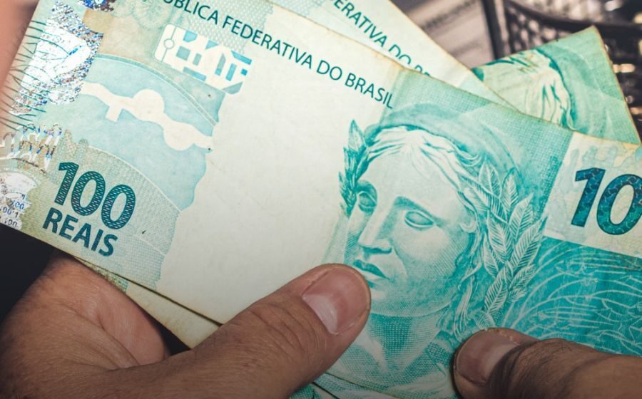 Calendário destacando 12 de outubro feriado Nossa Senhora Aparecida com balança de justiça e dinheiro