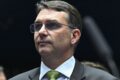 Flávio Bolsonaro em coletiva contestando resultado eleitoral com logo do PL ao fundo