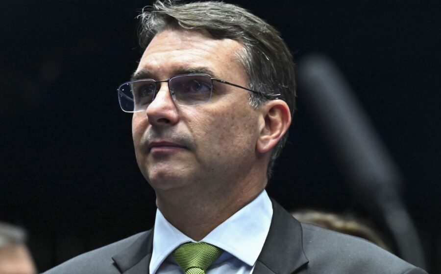 Flávio Bolsonaro em coletiva contestando resultado eleitoral com logo do PL ao fundo