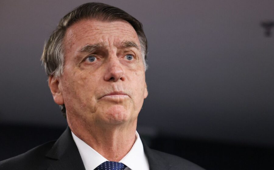 Flávio Bolsonaro discursa ao fundo logotipos da Caixa Econômica e Banco do Brasil